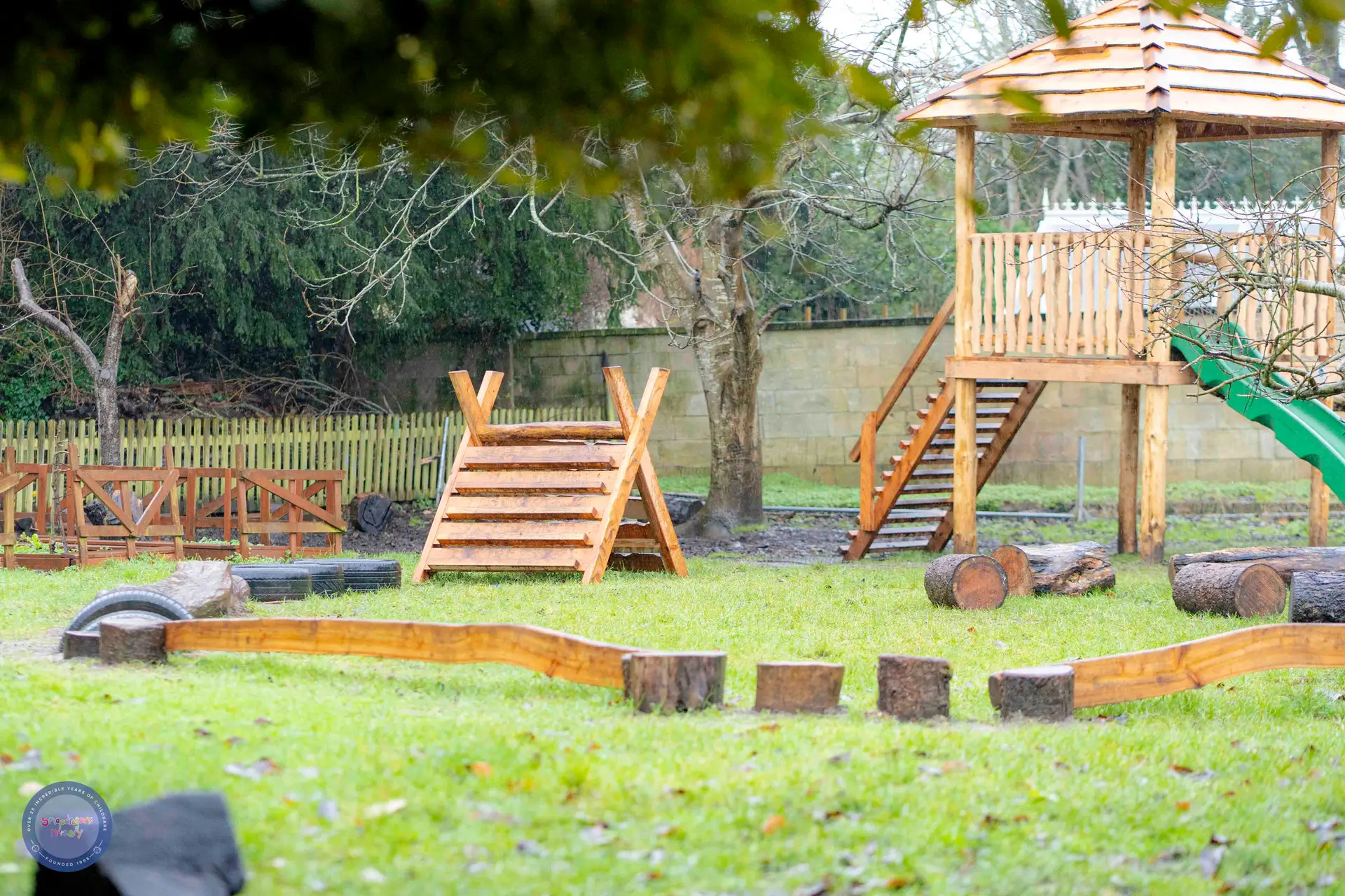 Completed timber play structure with ramp, platform and log edging built by Monkey Business Design at a Bath nursery